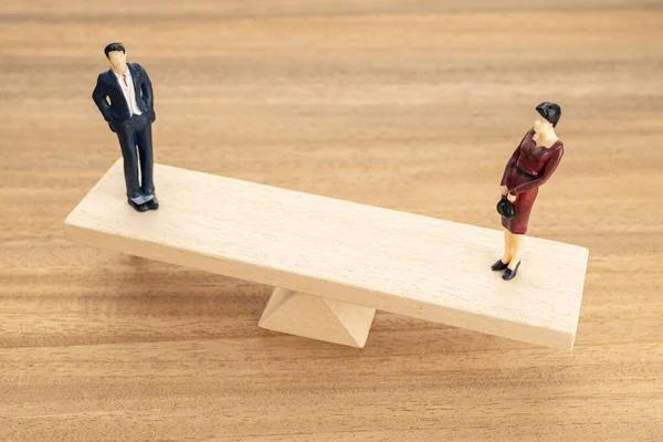 Gender equality concept. Man and woman figurine on wooden seesaw