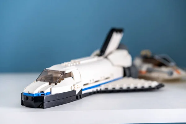 A selective focus shot of a Lego brand space shuttle toy on a white shelf