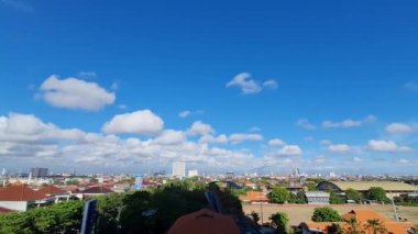 A beautiful view of a cityscape with modern buildings and green trees on a sunny day under the blue cloudy sky