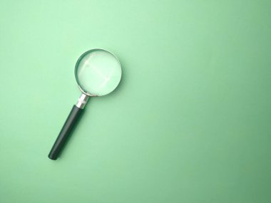 An isolated shot of a magnifying glass on a green background