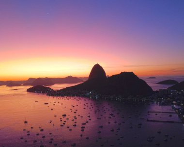 A mesmerizing view of cliffs and rocks in a small island with many boats in the sea during sunset