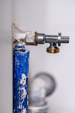 A vertical closeup of a grungy metal water pipe attached to a wall
