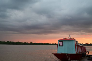 A boat moored near the pier on the sunset