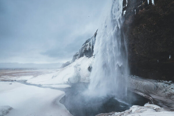 A waterfall with cloudy sky on the background