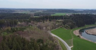 A drone footage of forested hills, fields and Chiemsee lake at afternoon