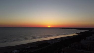 sunset with aerial drone shot in motion from the town and capturing when the sun sets in the sea