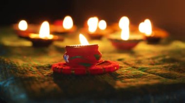 Diwali Diya oil lamps are placed on a table among other glowing Diya lamps. Decorative Diya lamps.