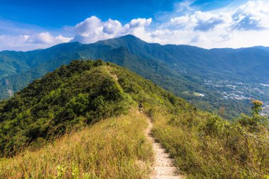 Dağ sıralarının güzel manzarası ve altında bulutlu gökyüzü olan bir kasaba.