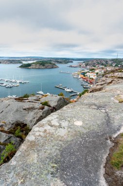 A vertical shot from above a rock of yachts and boats in a harbor under cloudy sky in Sweden