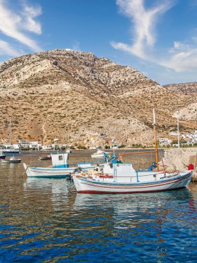 A beautiful shot of the moored small wooden boats at the beach of Kamares village in bright sunlight in Sifnos island, Greece