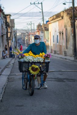 A vertical view of a senior Hispanic flower seller with his bike on the street