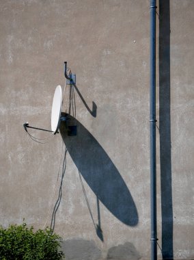 Uzun gölgeli bir ev duvarında uydu anteni