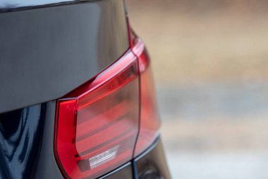 A closeup of a black car's red taillight on a blurry background