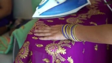 A closeup of female ironing a Hindu traditional purple dress