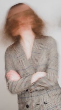 Klasik gri spor ceketli ve kırmızı rujlu, gri arka planda hareket eden zarif kıvırcık bir kızın yavaş çekim hızı.