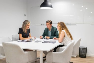 Modern bir iş merkezinin içinde iş tartışan üç iş arkadaşı.