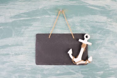 White anchor on an empty sign, blue textured background, maritime sea life, sailing trip, summer vacation, tourism concept, harbor