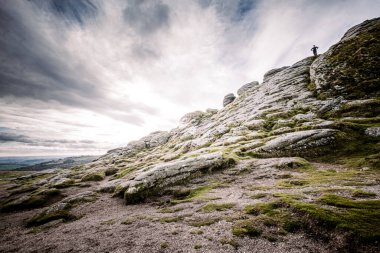 A man standing on top of the rocky sloping side of Haytor Tor in Dartmoor