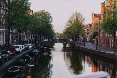 Hollanda, Amsterdam 'da sakin bir nehir üzerinde eski binaların manzarası ve bir köprü.