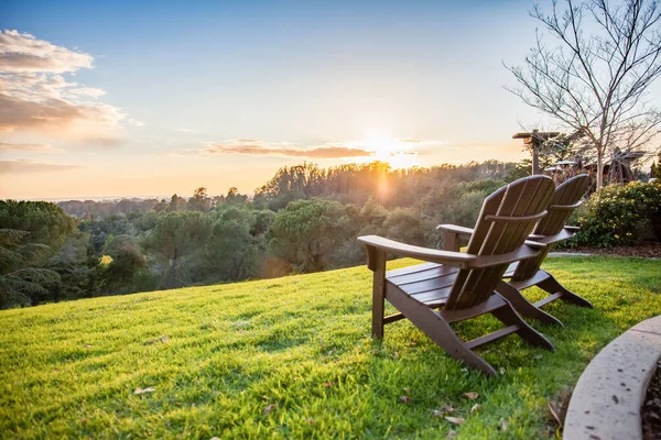 A scenic view of a sunrise over the green hills and garden chairs- vacation concept
