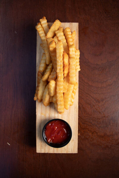 Вид сверху на картошку фри с кетчупом на деревянном столе