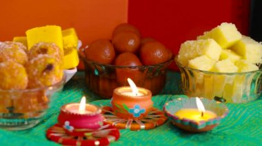 Colorful Diwali oil lamps, Deepavali oil lamps lighted in beautiful formation with bowls full of different Diwali sweets . Decorative Colorful Diya