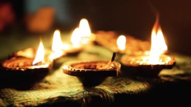 Diwali Diya oil lamps are placed on a table among other glowing Diya lamps. Decorative Diya lamps.