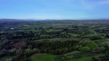 Drone flight over a typical Tuscan landscape with green hills, cypress, vineyards and the agricultural farms with buildings made of natural stone