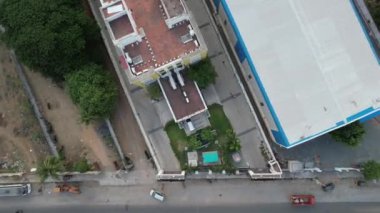 A bird's eye view of the roofs of buildings near an asphalt road