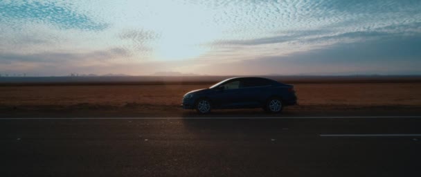 別のミニバンを背景に砂漠を通過して道路上の車の遠くの景色 — ストック動画