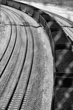 a vertical grayscale shot of train with coal on railway