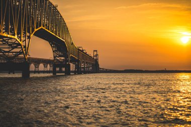 A beautiful view of a bridge over a tranquil water during a scenic sunset