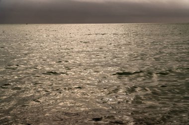 A scenic view of a vast ocean in cloudy sky background