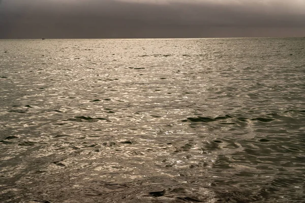 A scenic view of a vast ocean in cloudy sky background