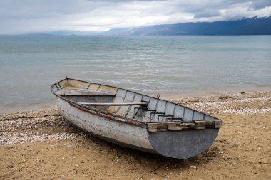 A beautiful shot of an old rusty boat at the shore of a lake