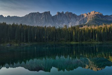 An aerial view of lake surrounded by trees in background of rocky mountains