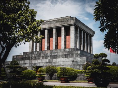 A beautiful shot of the design of Ho Chi Minh Mausoleum under a cloudy sky with trees and plants