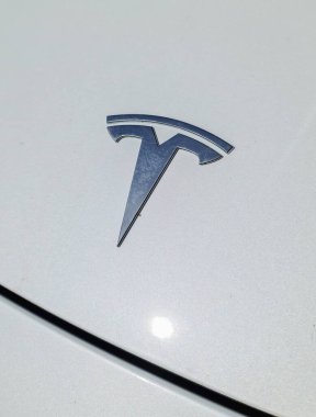 A Tesla logo on the hood of a white Tesla vehicle