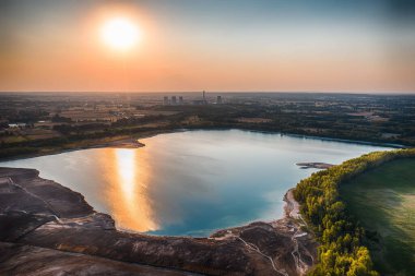 A mesmerizing view of a beautiful Lake at the mine in Turku surrounded by green landscape during sunset