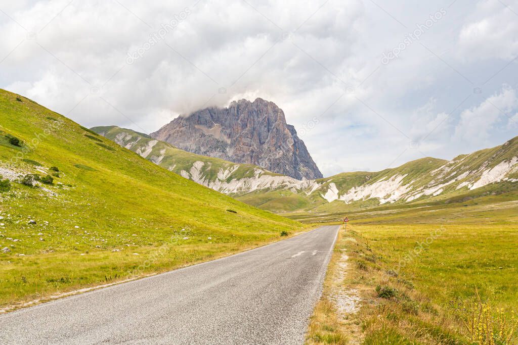 An empty road in Campo Imperatore valley with Gran Sasso mountain in background in Abruzzo, Italy