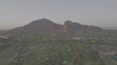 Push in shot of Camelback Mountain at sunrise in Phoenix, Arizona drone fly over golf course and luxury homes. Dlog, Pro Res 422
