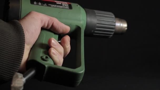 黒を背景にヴィンテージの熱風銃を操作する手 — ストック動画