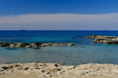 A beautiful view of the sea with ships on the horizon from the rocky shore