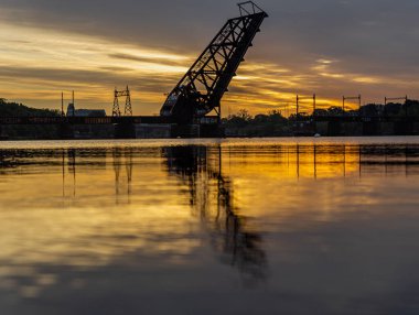 A beautiful view of a railway bridge on Rhode island next to a river and sunset on the horizon