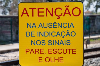 A yellow information board for the crossing the train line