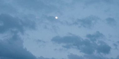 A video of the full moon in the cloudy sky at blue hour
