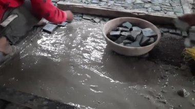 skilled builders put crazy Crazy paving ceramic tiles on the wet concrete floors. Worker putting crazy Crazy paving ceramist tile on the floor.