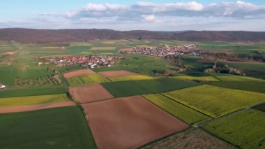 Almanya 'nın Bavyera kentindeki güneşli bir günde yeşil tepelere karşı tarımsal tarlalara kuş bakışı bakış