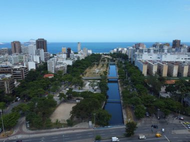 Drone view of buildings and water canal with vegetation in a city under clear sky
