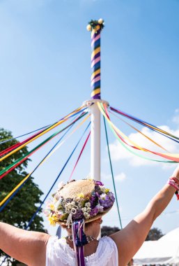 A vertical shot of female in a traditional English hat dancing with a maypole at the Countryfile Live